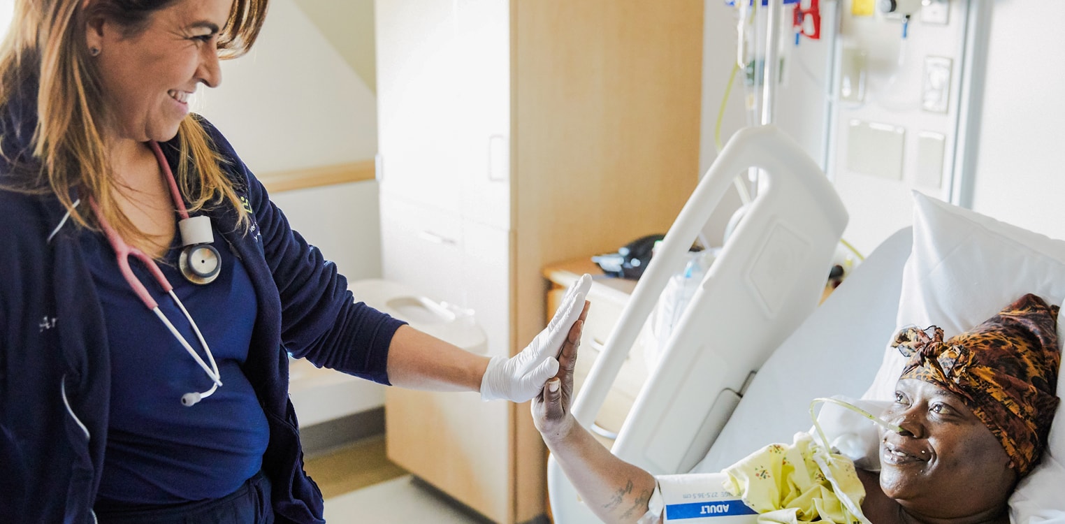 Nurse gives a high-five to a patient in a hospital bed