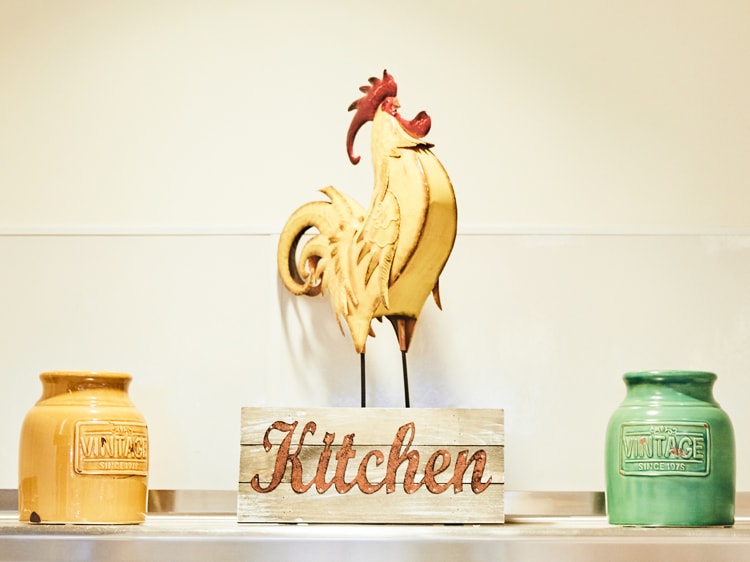 Sculpture of a crowing rooster on a block that reads kitchen