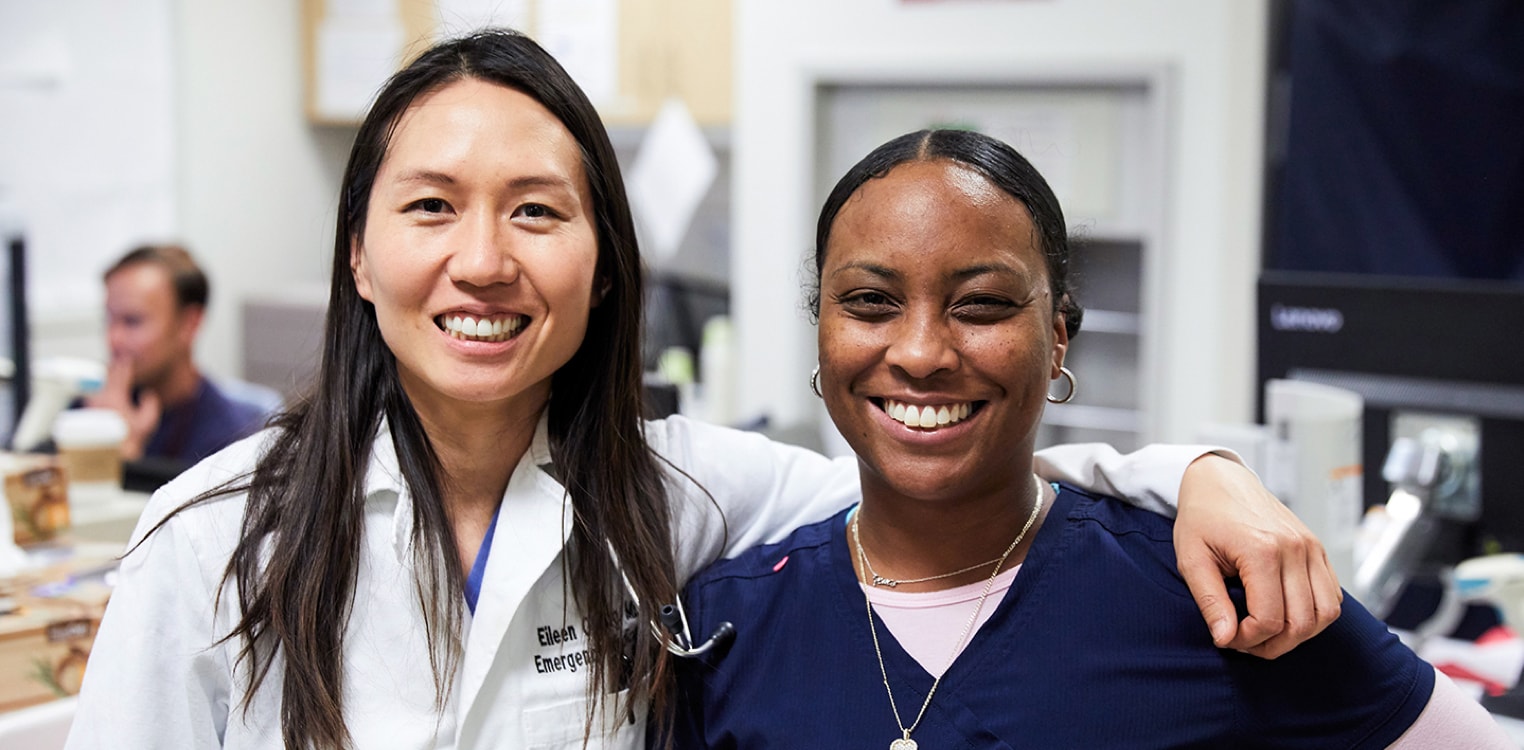 Smiling female physician and smiling female nurse side by side