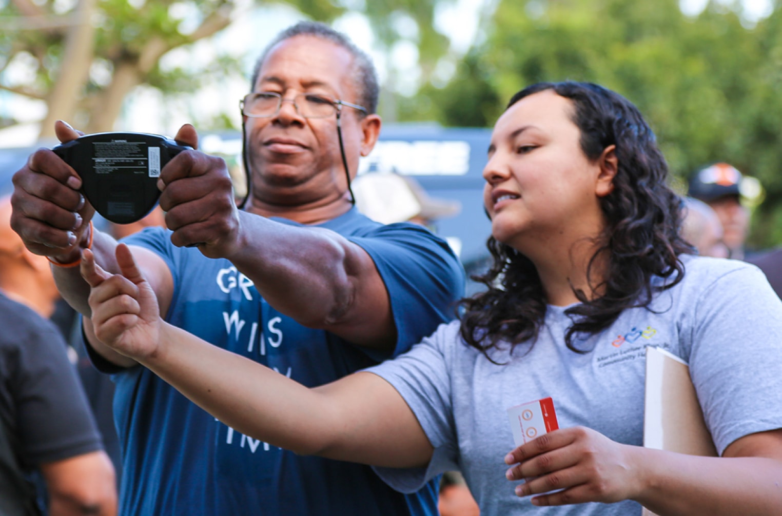 An MLKCH volunteer shows a man his readings on a screening device at a community event