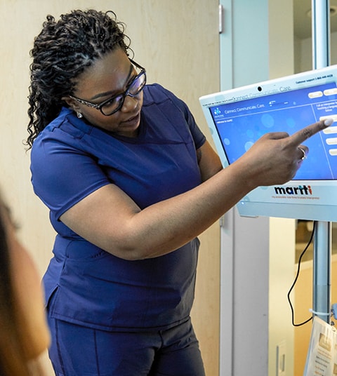 Black female nurse pointing at screen of interpretation machine