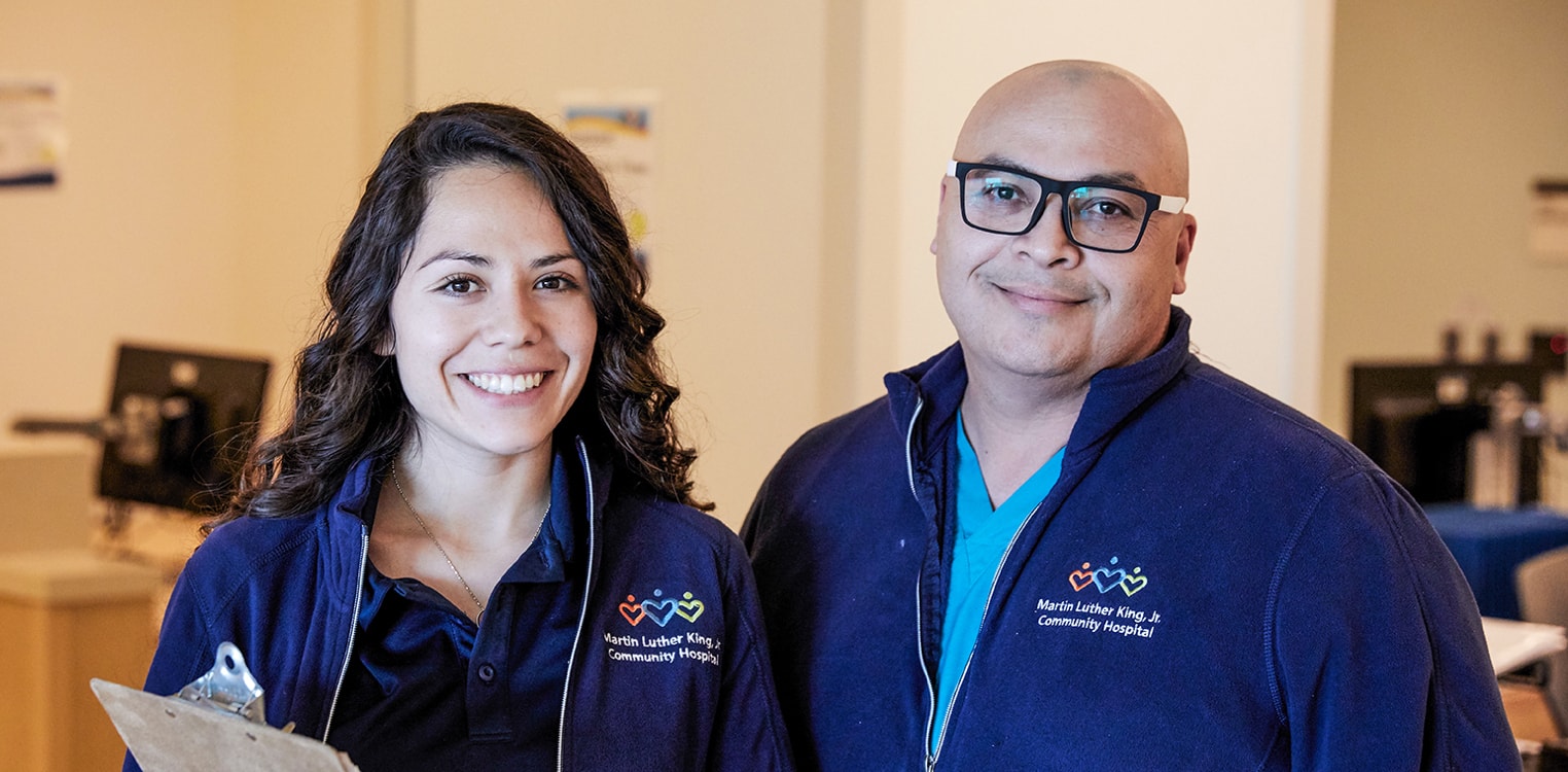 Dos latinos, voluntarios del hospital, sonriendo