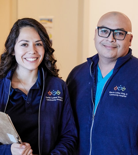 Smiling Latinx male and female wearing MLKCH jackets