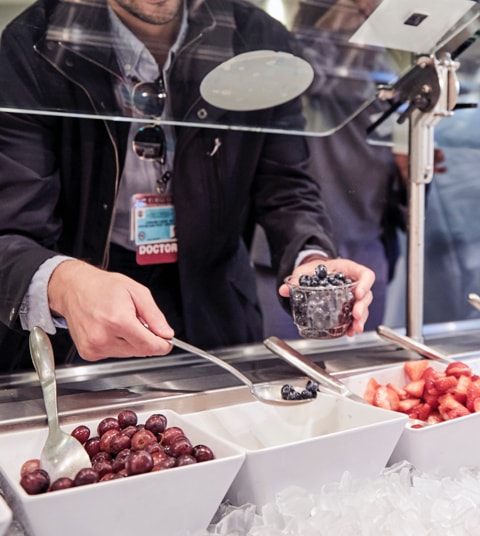 Close up of hands scooping blueberries at a salad bar