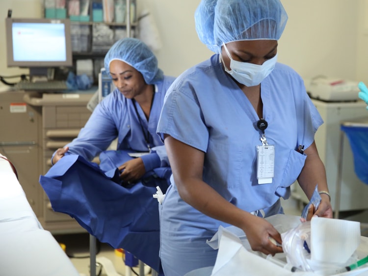 Dos enfermeras, que usan ropa de hospital descartable, preparan un quirófano para una cirugía