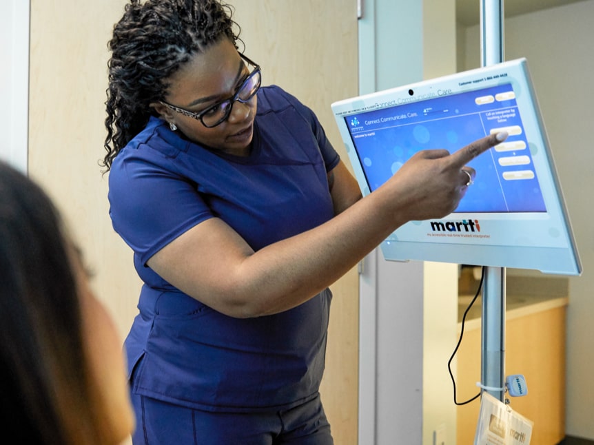 Black female nurse pointing at medical translation device