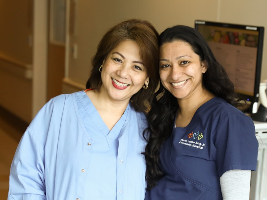 Two Asian nurses wearing scrubs and smiling