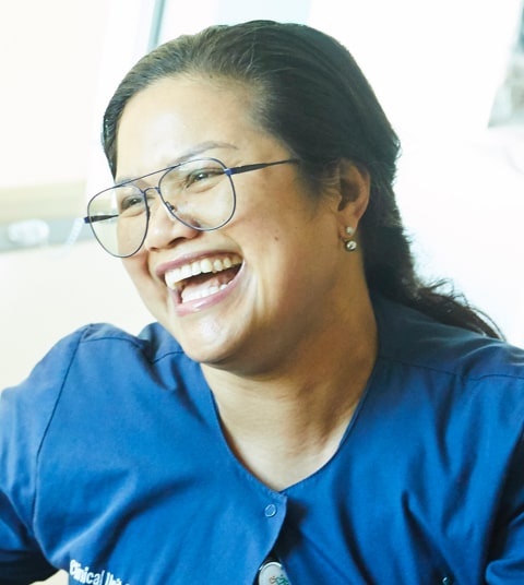 Laughing Asian female nurse in blue scrubs