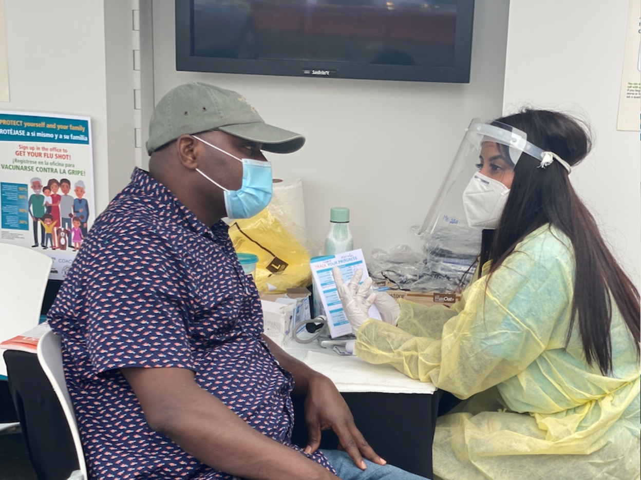 Photo of a masked patient with masked nurse