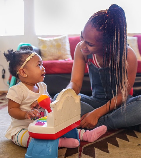 A smiling mother with her child playing on the floor