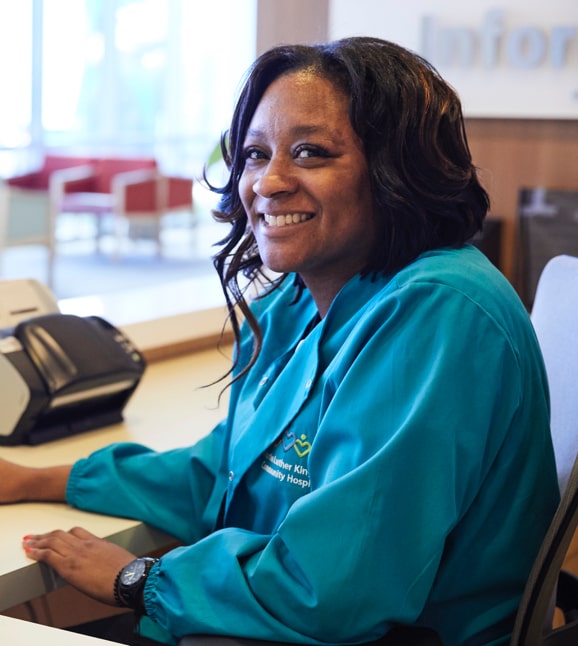 Una enfermera joven de color sonriendo sentada en un escritorio