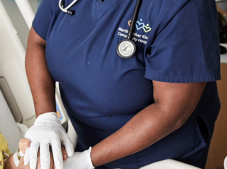 Close up of Black nurse's gloved hands holding patient's hands