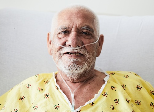 Primer plano de un paciente latino mayor con cánula nasal