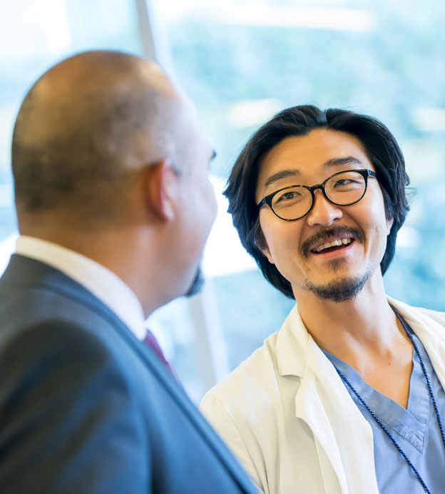 Asian male doctor smiling at another male doctor