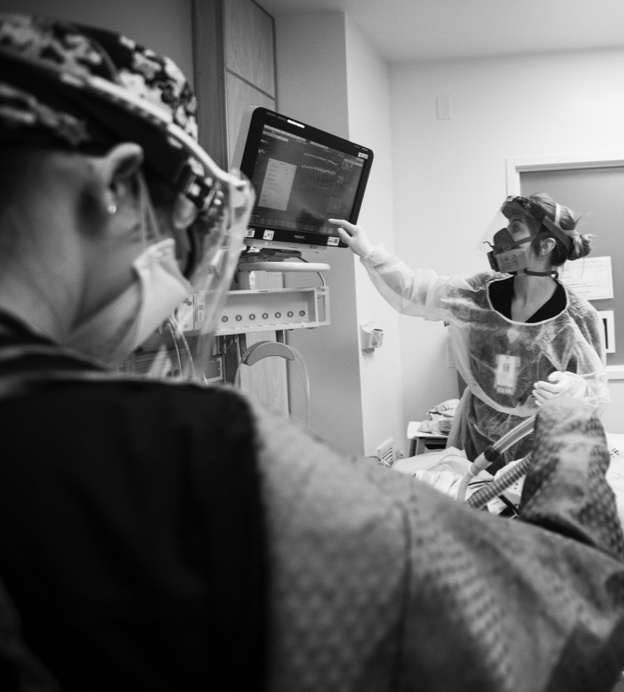 Black and white photograph of nurses in full PPE in a hospital room 