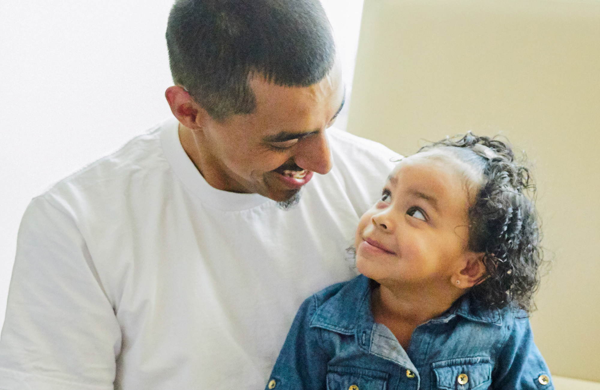 Padre latino sonriendo a su hija pequeña