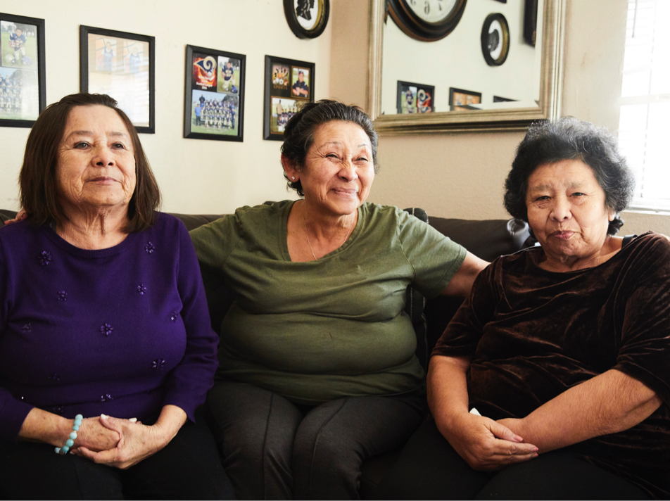 Tres hermanas latinas y mayores sentadas en su hogar