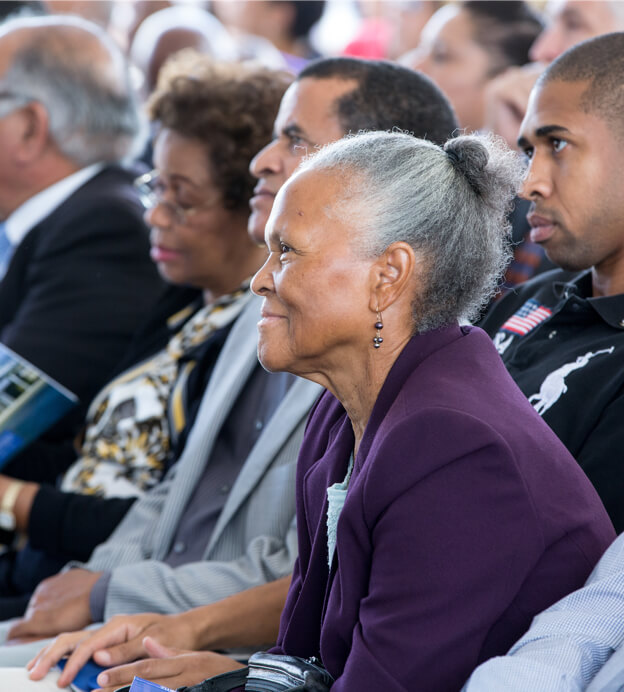 Close up of older Black woman with gray hair in bun seated in the crowd