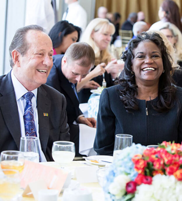 Older white man seated next to middle-aged Black woman smiling at the Dream Lunch