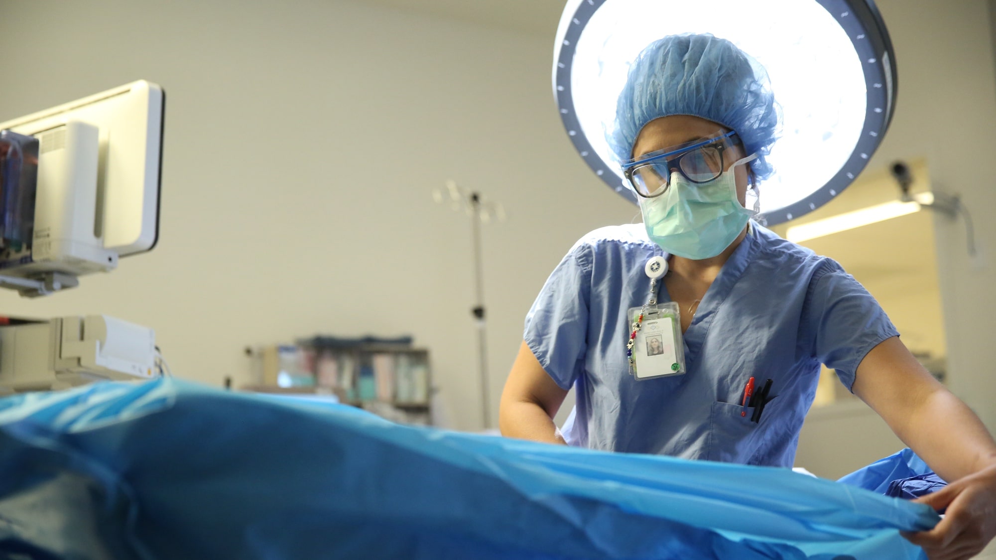 Female nurse in blue scrubs and protective gear in operating room