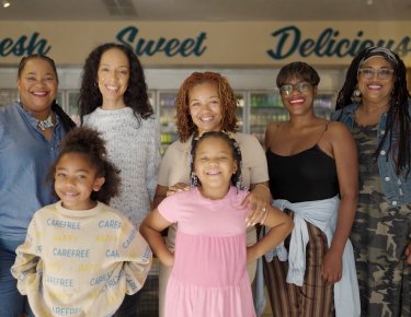 Photo of a group of women & children smiling in the market