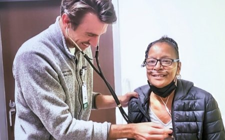 AA woman sitting with doctor listening to her heart