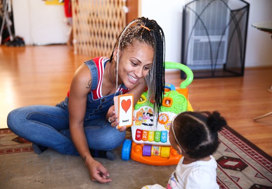 Close up of Black mother showing her baby a flash card that reads heart
