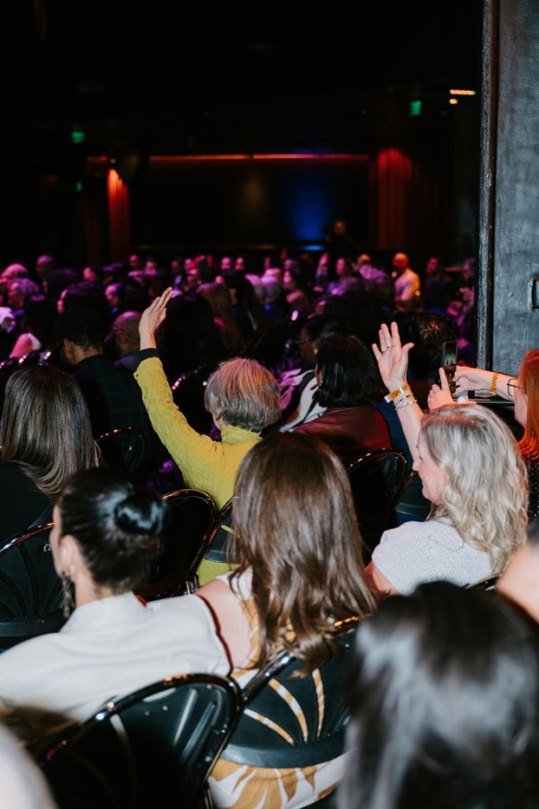people raising their hands in audience