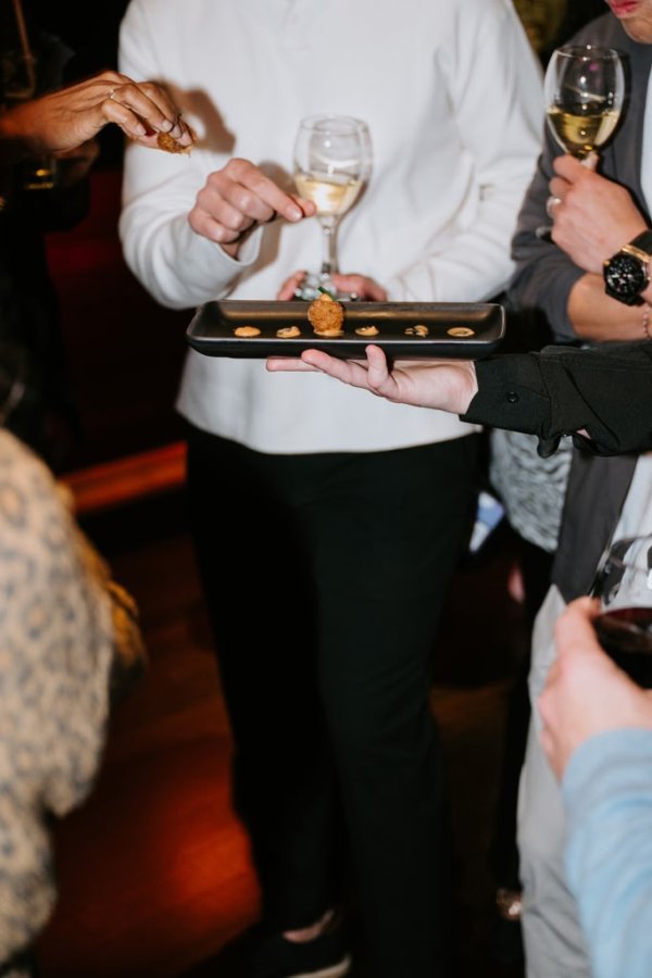 people grabbing appetizers off of a tray