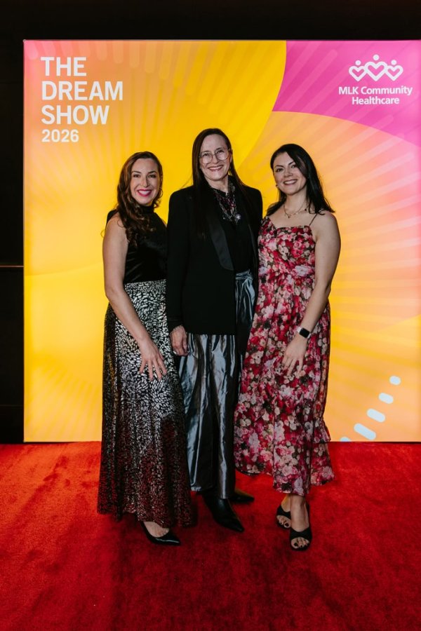 group of women smiling in front of photo backdrop