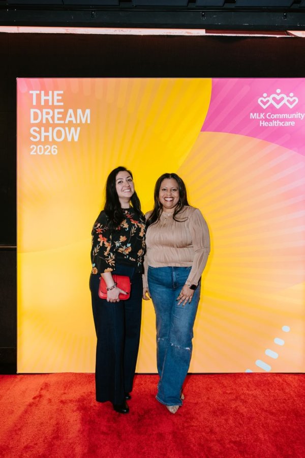 2 women smiling in front of photo backdrop