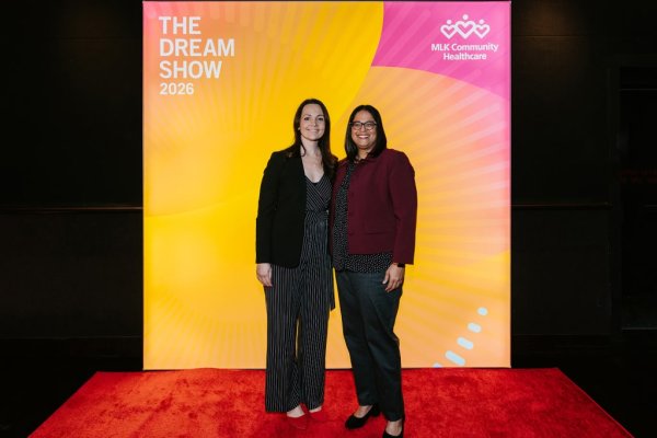 2 women smiling in front of photo backdrop