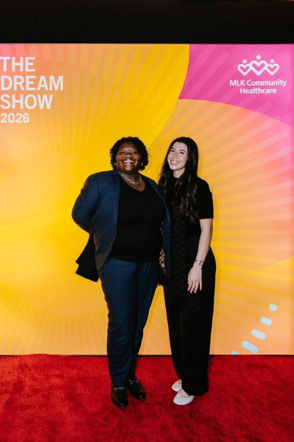 2 women smiling in front of photo backdrop