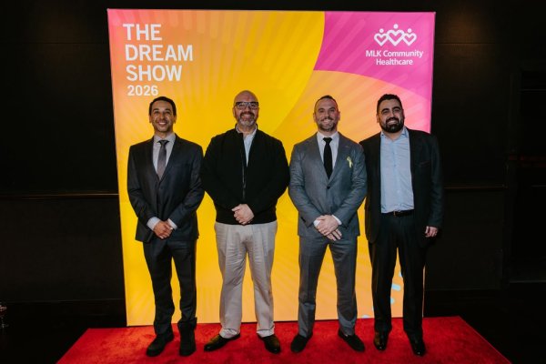 group of men smiling in front of photo backdrop