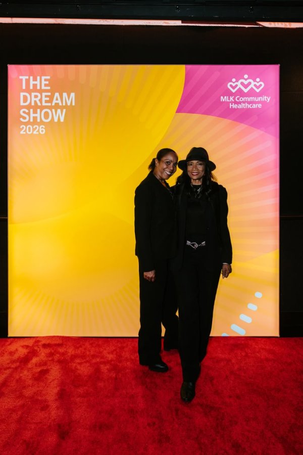 2 women smiling in front of photo backdrop