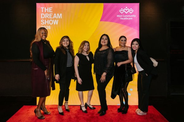 group of women smiling in front of photo backdrop