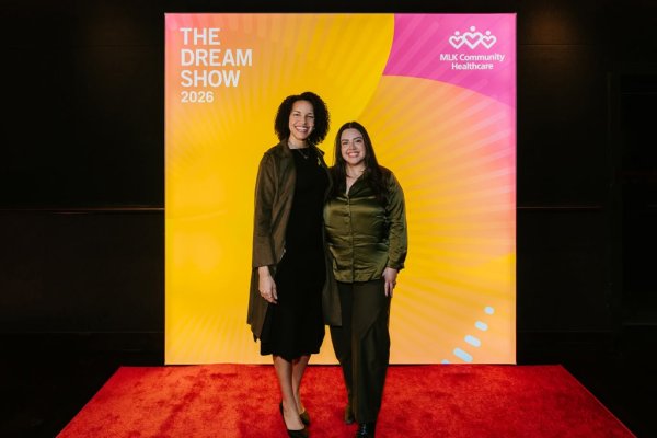2 women smiling in front of photo backdrop