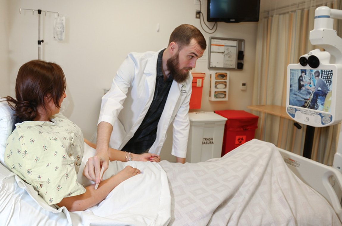 Telemedicine device in use with a female patient in a hospital bed