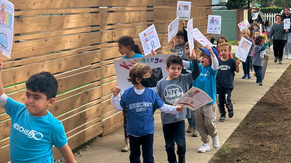 Kids walking down a sidewalk holding hand painted signs