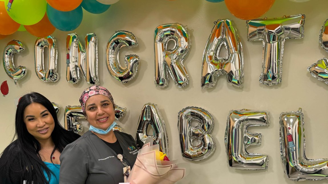 Image of 2 women smiling in front of balloons that say "Congratulations Yesabel"