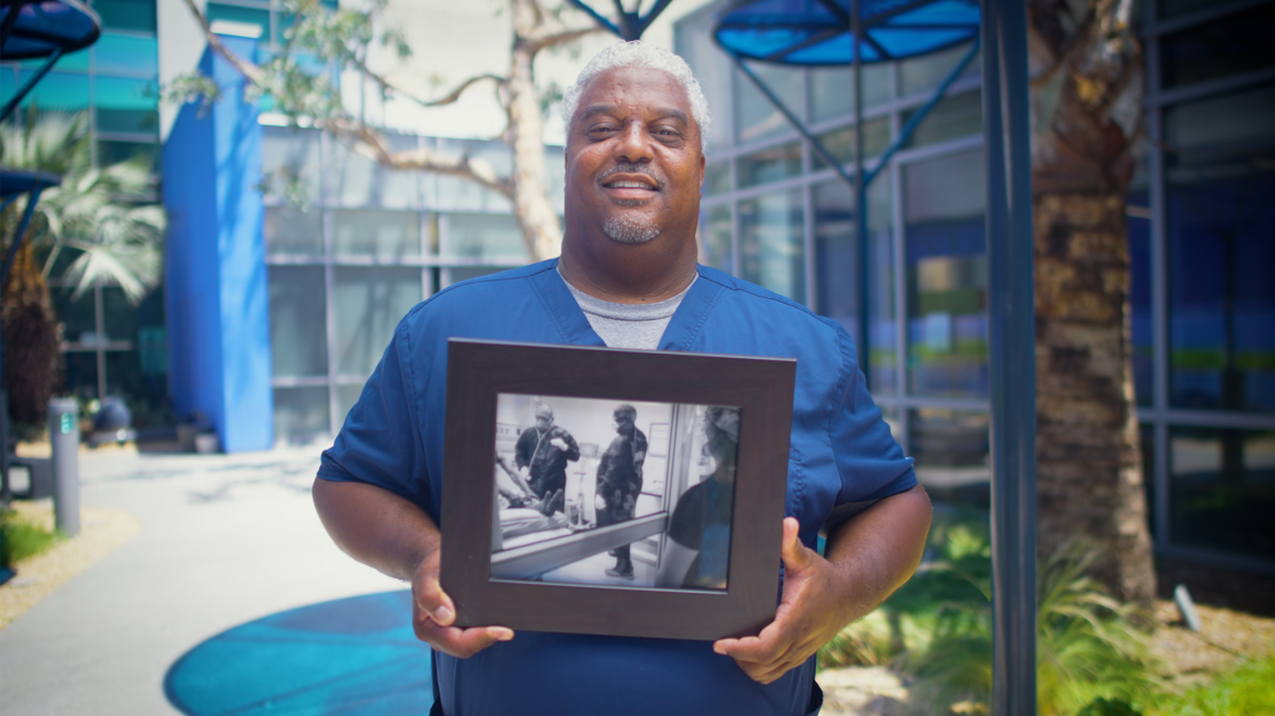 Man holding a photo of himself during COVID