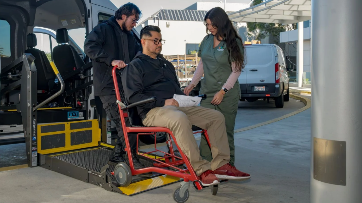 Man being pushed in a chair by a transporter and nurse