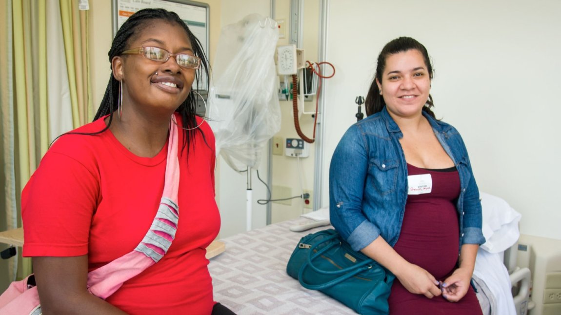 Two young women sitting on a hospital bed 