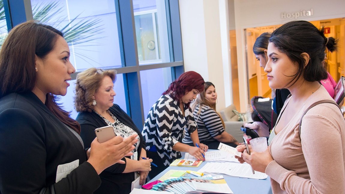 Female maternity tour attendees speaking at information table 