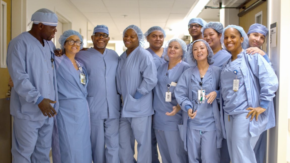 Group of eleven surgical techs and nurses in blue scrubs