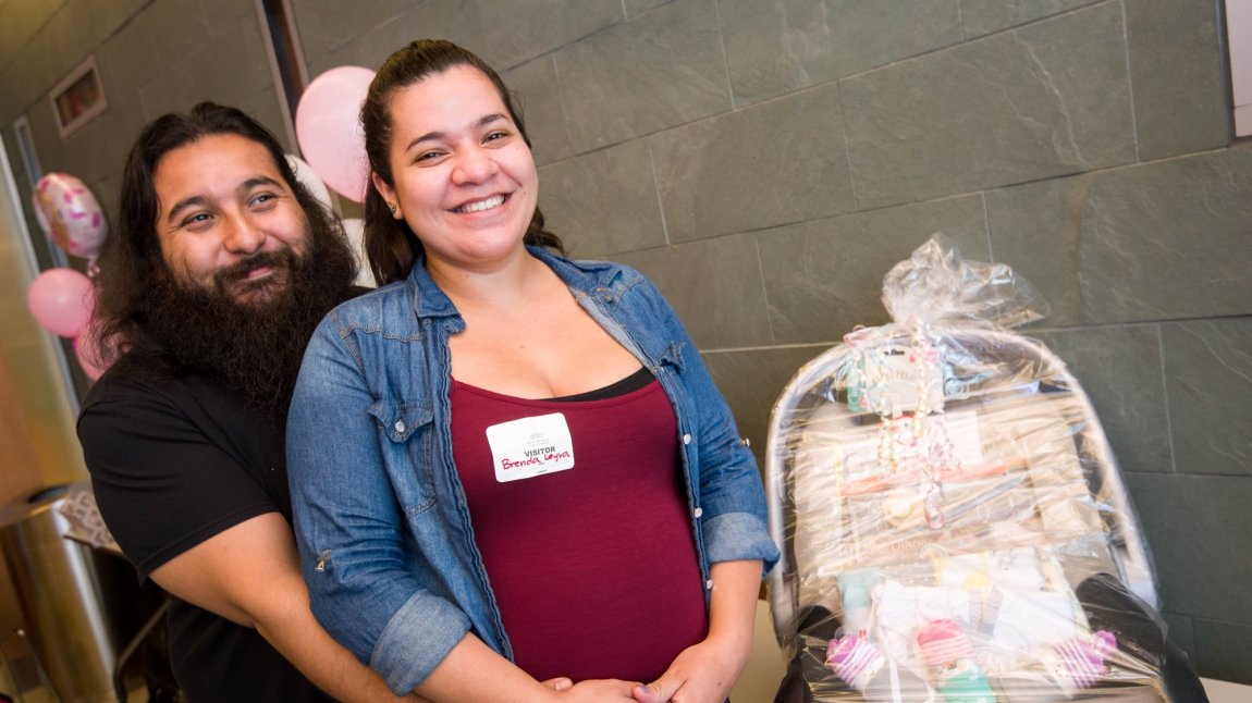 Smiling pregnant woman and partner sitting next to gift basket