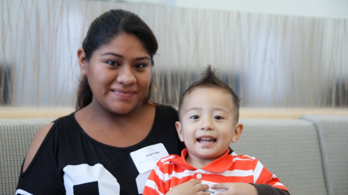 Young Latina mom holding smiling son