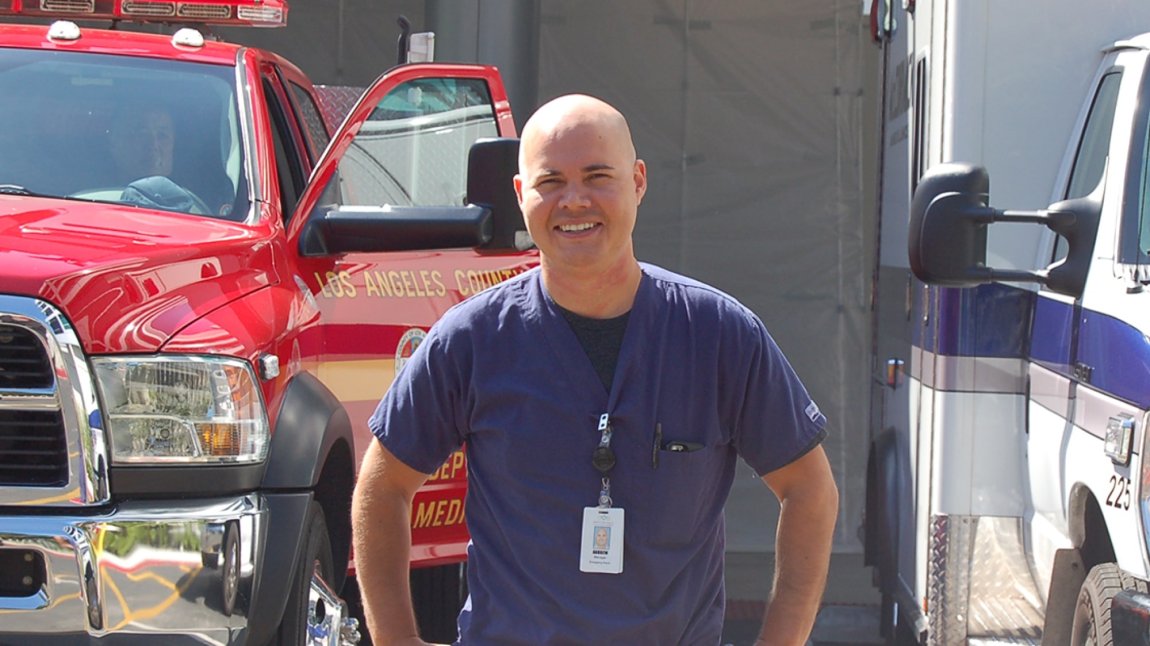 Latino nurse standing in front of fire department truck