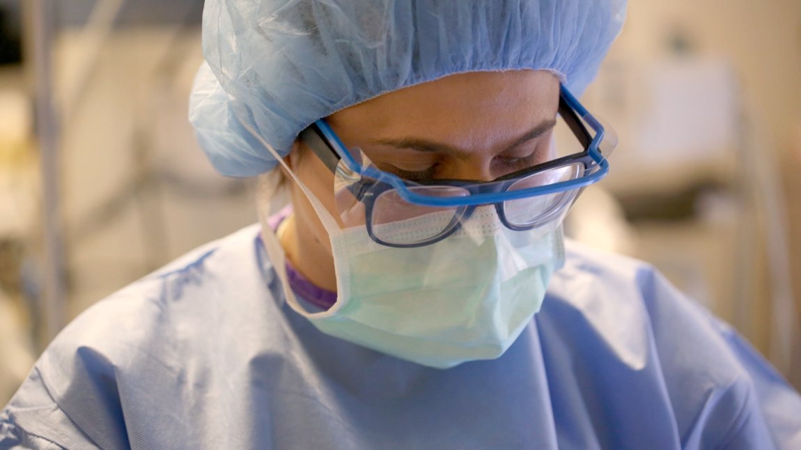 Close up of female nurse wearing glasses, face shield, and mask