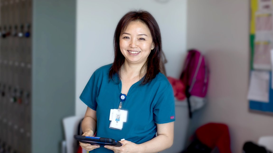 Smiling asian female nurse in blue scrubs